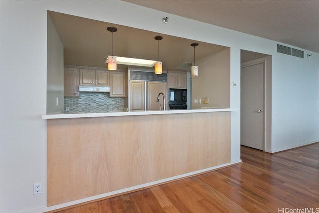 kitchen featuring visible vents, decorative backsplash, built in appliances, a peninsula, and under cabinet range hood