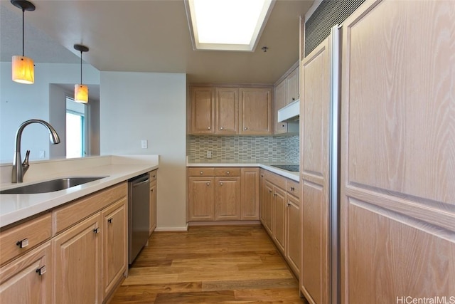 kitchen with paneled built in fridge, dishwasher, light wood-style floors, under cabinet range hood, and a sink