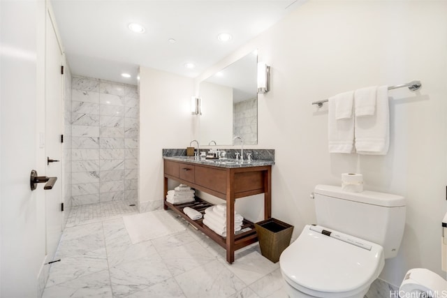 bathroom with vanity, a tile shower, and toilet