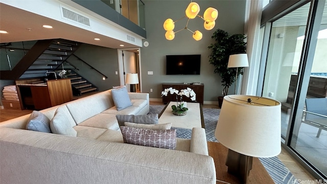 living room featuring hardwood / wood-style flooring, a towering ceiling, and a chandelier