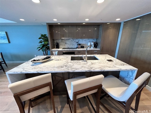 bar with tasteful backsplash, sink, and light wood-type flooring