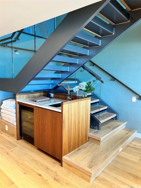 bar with light hardwood / wood-style flooring and beverage cooler