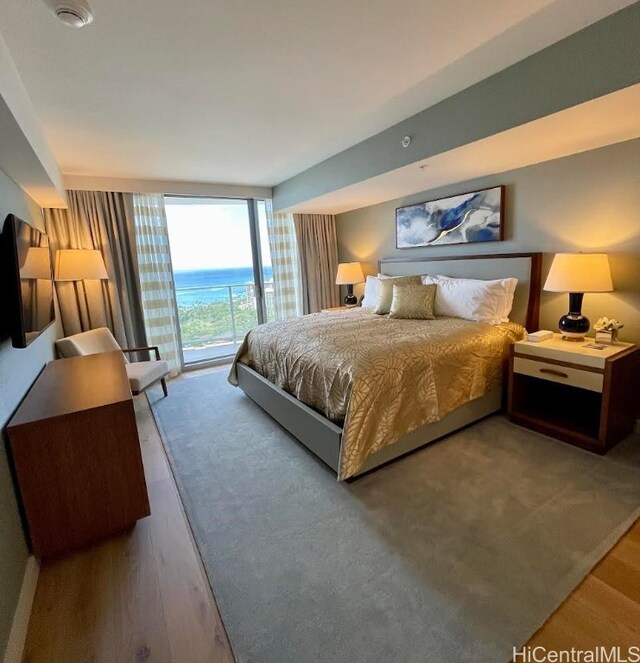 bedroom featuring hardwood / wood-style flooring, access to outside, and a wall of windows