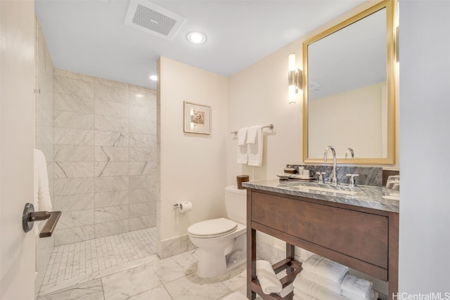 bathroom with toilet, vanity, and a tile shower