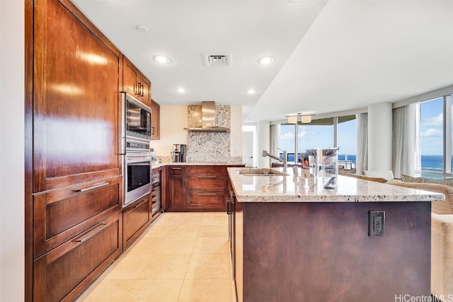 kitchen with wall chimney range hood, sink, stainless steel appliances, a water view, and decorative backsplash