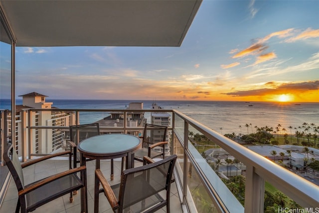 balcony at dusk featuring a water view