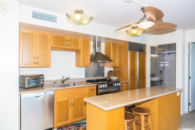 kitchen featuring dishwashing machine, stainless steel range, wall chimney range hood, a kitchen island, and a breakfast bar area