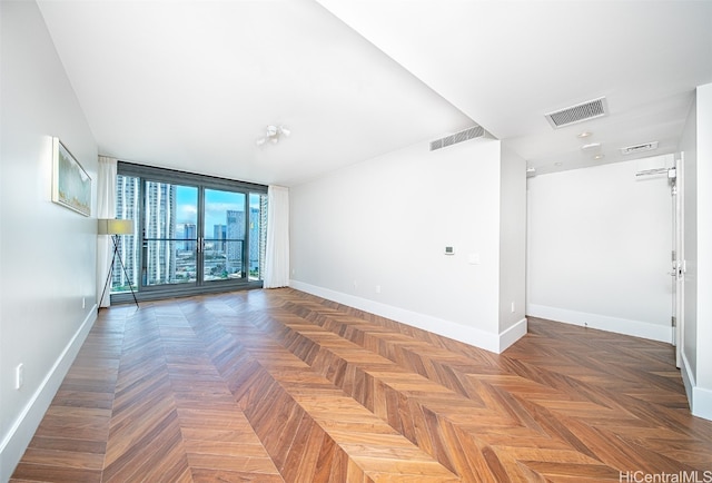 empty room featuring dark parquet flooring and floor to ceiling windows