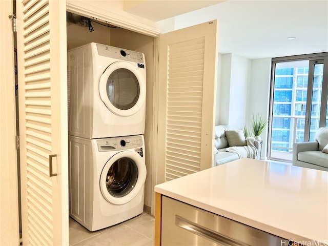 washroom with stacked washer / drying machine, light tile patterned flooring, and plenty of natural light