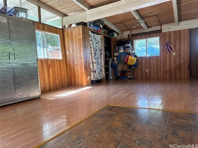 empty room featuring dark wood-type flooring, wooden walls, wooden ceiling, and plenty of natural light