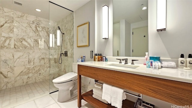 bathroom featuring vanity, a tile shower, toilet, and tile patterned floors