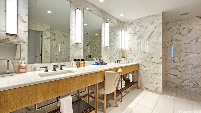 bathroom with a tile shower, vanity, tile walls, and tile patterned flooring