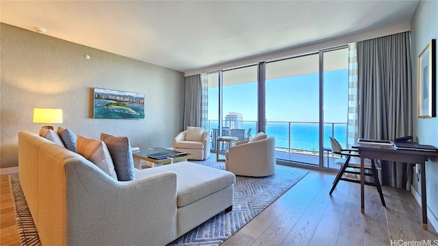 living room featuring expansive windows, wood-type flooring, and a water view