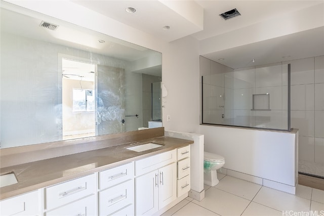 bathroom featuring vanity, toilet, tile patterned floors, and tiled shower