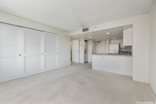 unfurnished living room featuring a textured ceiling and light colored carpet