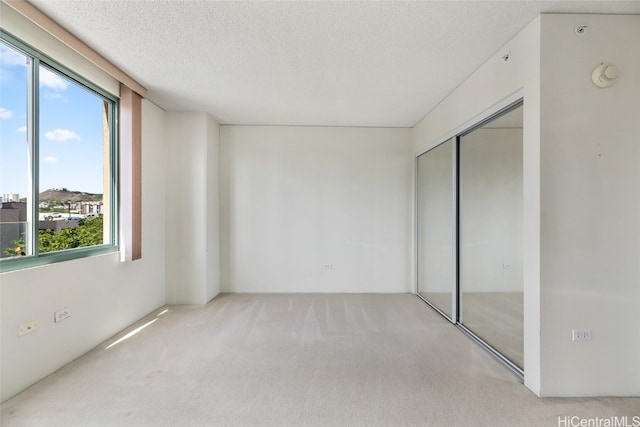 carpeted spare room with a textured ceiling and a healthy amount of sunlight