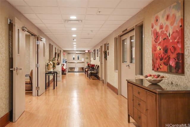 hallway with a paneled ceiling and light wood-type flooring