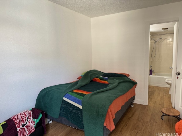 bedroom featuring connected bathroom, hardwood / wood-style flooring, and a textured ceiling