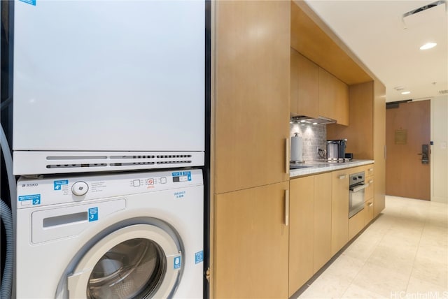 washroom featuring light tile patterned flooring and stacked washer and clothes dryer