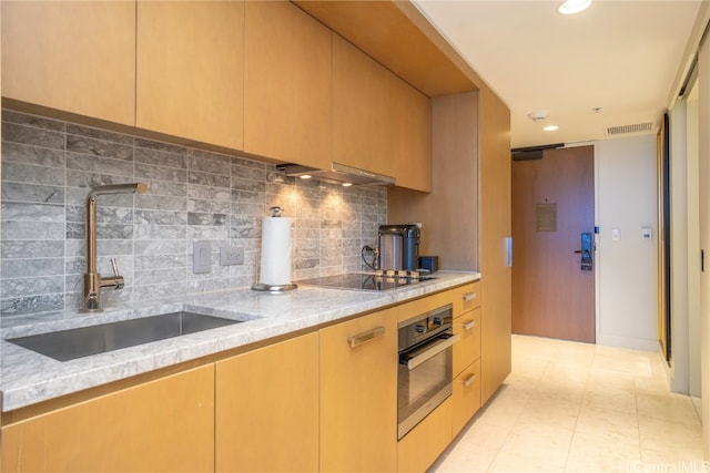 kitchen featuring black electric stovetop, stainless steel oven, sink, light stone countertops, and tasteful backsplash