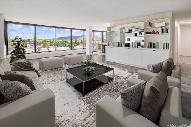 living room with a wall of windows, light hardwood / wood-style flooring, and a textured ceiling