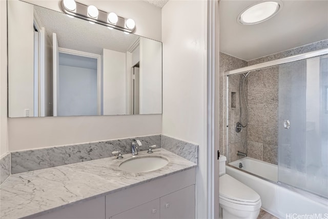 full bathroom featuring toilet, a textured ceiling, vanity, and shower / bath combination with glass door