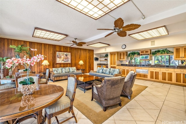 interior space featuring a textured ceiling, wooden walls, sink, and ceiling fan