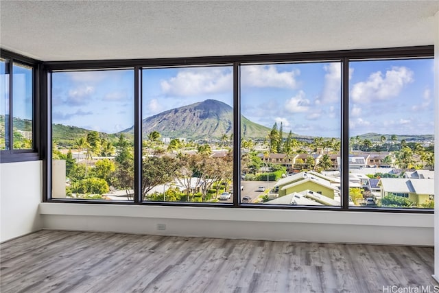 spare room with a mountain view, a healthy amount of sunlight, a textured ceiling, and light hardwood / wood-style floors