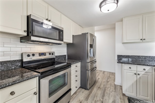 kitchen featuring backsplash, dark stone counters, white cabinetry, appliances with stainless steel finishes, and light hardwood / wood-style floors