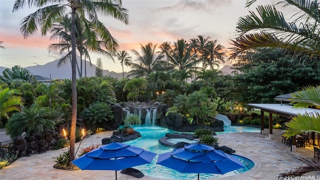 pool at dusk with a patio area