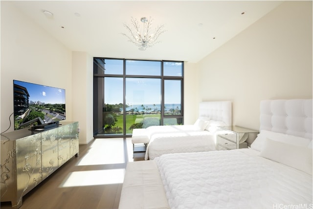 bedroom with a notable chandelier, wood-type flooring, and floor to ceiling windows