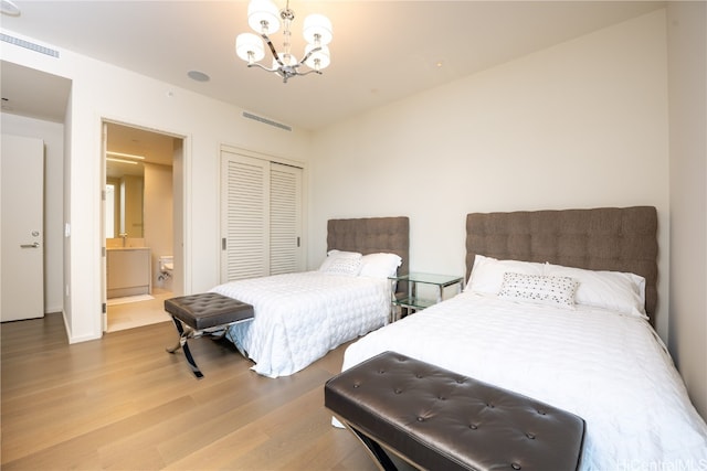 bedroom featuring a closet, hardwood / wood-style flooring, a chandelier, and connected bathroom