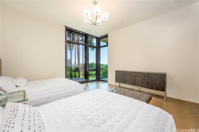 bedroom featuring a notable chandelier, hardwood / wood-style floors, and a wall of windows