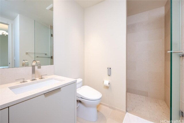 bathroom with vanity, toilet, and tiled shower