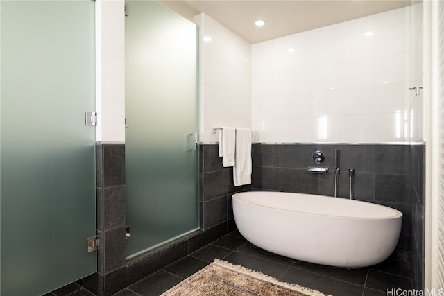 bathroom with tile patterned floors, tile walls, and separate shower and tub