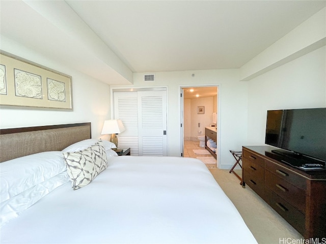 bedroom featuring connected bathroom, light colored carpet, and a closet