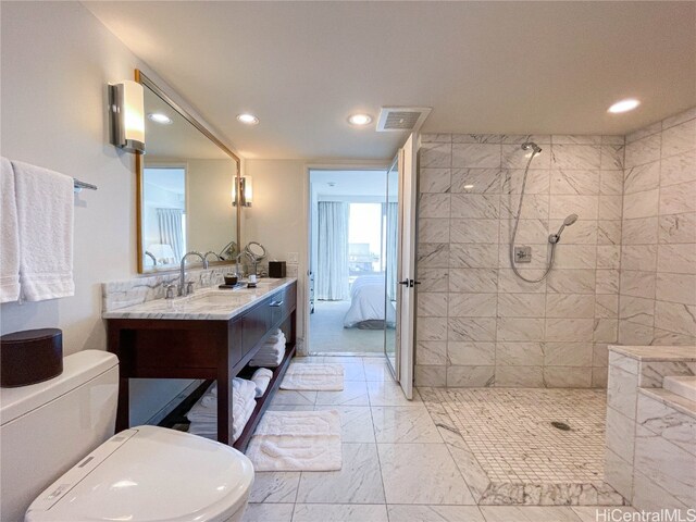 bathroom with vanity, tiled shower, and toilet