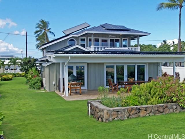 back of house with a yard, a patio, a balcony, and solar panels