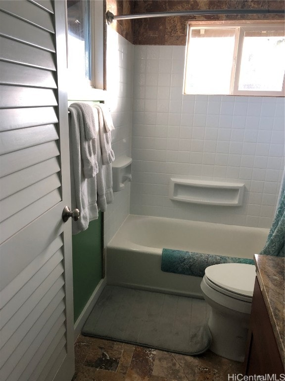 full bathroom with vanity, tiled shower / bath, and toilet