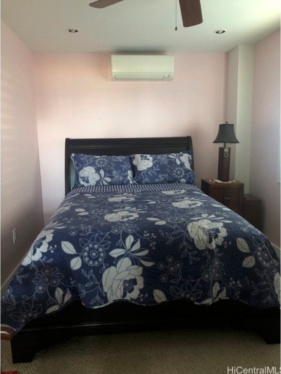 carpeted bedroom with a wall unit AC and ceiling fan