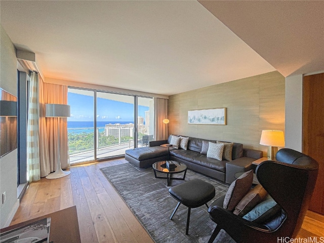 living room featuring a water view, light wood-type flooring, and floor to ceiling windows