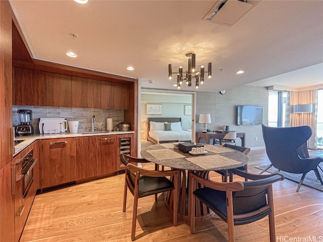 kitchen featuring decorative backsplash, light hardwood / wood-style flooring, wine cooler, sink, and a chandelier