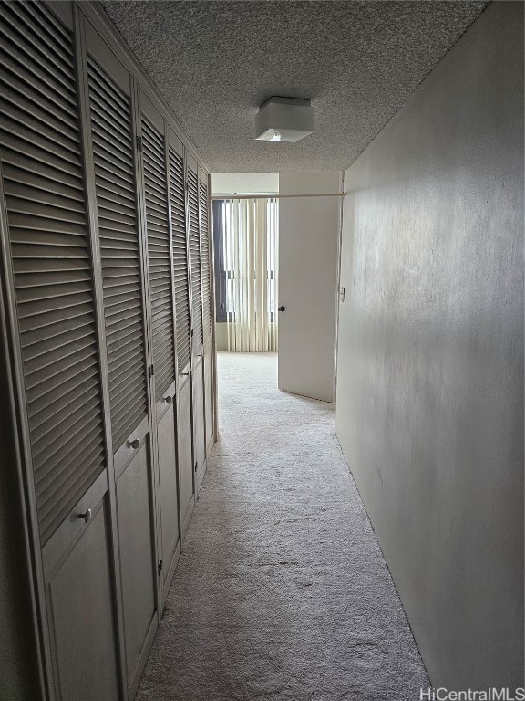 corridor featuring a textured ceiling and light colored carpet