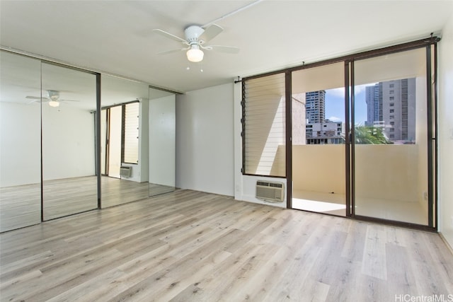 spare room with light hardwood / wood-style floors, expansive windows, and ceiling fan