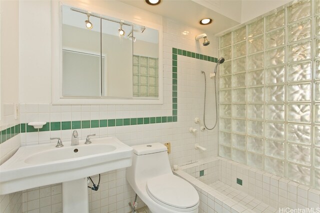 bathroom with toilet, tile walls, and tiled shower