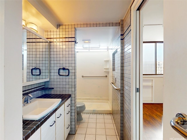 full bath with vanity, tile patterned flooring, a shower, toilet, and tile walls