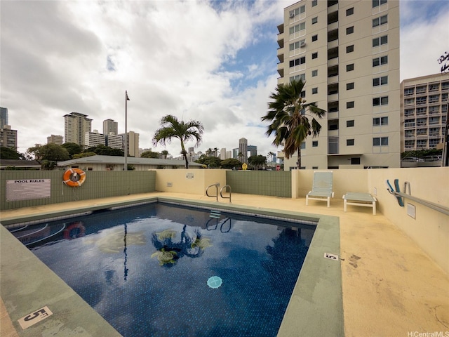 community pool featuring a view of city and fence