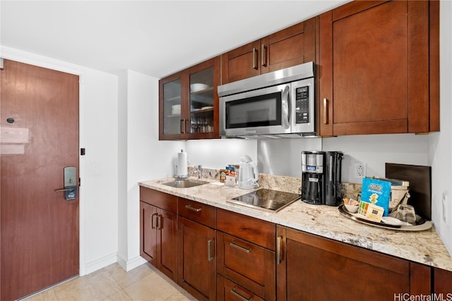 kitchen with black electric cooktop, light stone countertops, light tile patterned flooring, and sink