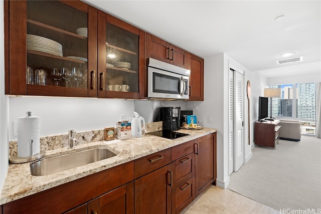 kitchen with light stone counters, sink, black electric cooktop, and light colored carpet