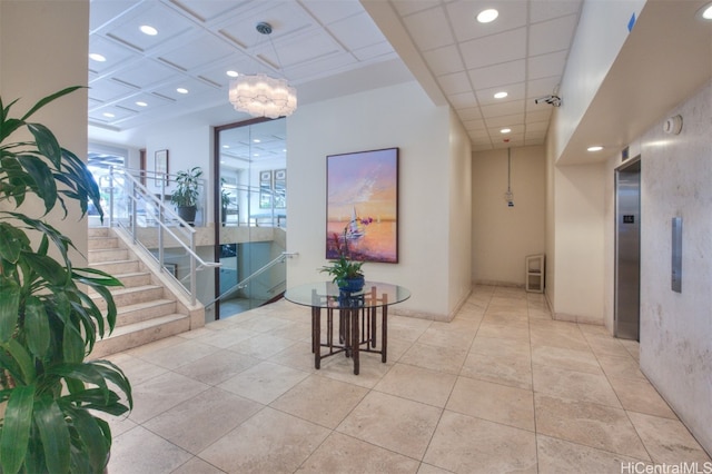 hall with an inviting chandelier, elevator, and light tile patterned floors